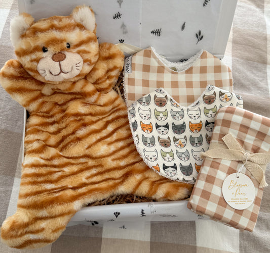 Baby gift box including a plush ginger cat comforter, gingham baby bib, another bib with cat faces and a gingham swaddle.
