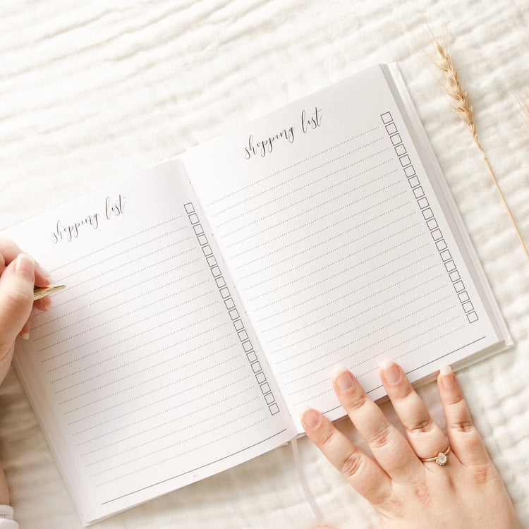 This pregnancy journal is opened to a double page which says 'Shopping list' at the top. There is lined pages with check boxes to write down all of the essentials and items you need to purchase for your baby.