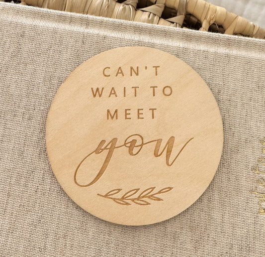 Round wooden plaque with 'Can't wait to meet you' text.