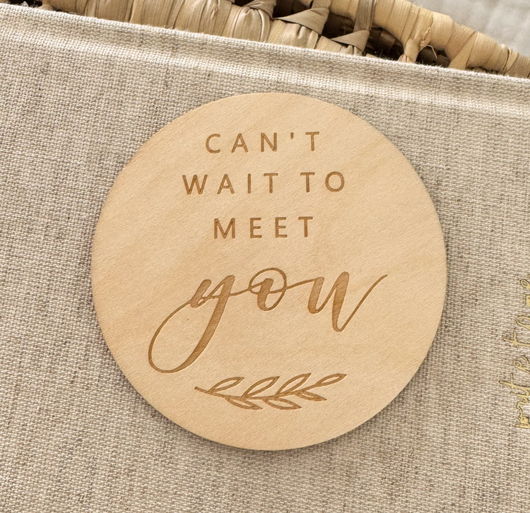 Round wooden plaque with 'Can't wait to meet you' text.