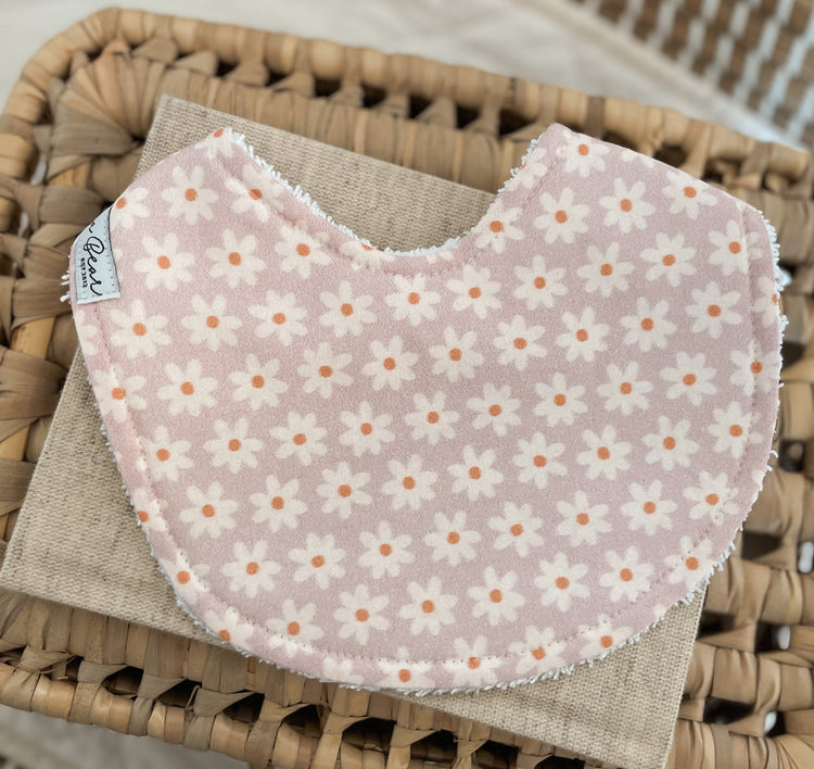 Handmade lilac baby bib with a repeating white daisy floral pattern; backed with absorbent terry towelling, ideal for dribble, teething, and newborn gifts.