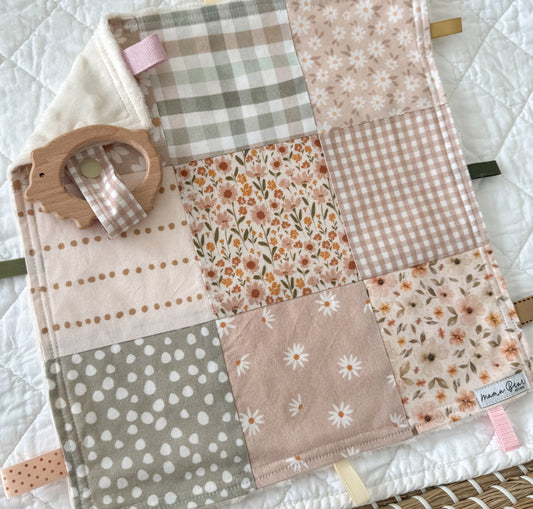 Patchwork baby blanket with floral, plaid, and polka dot patterns on a white background.