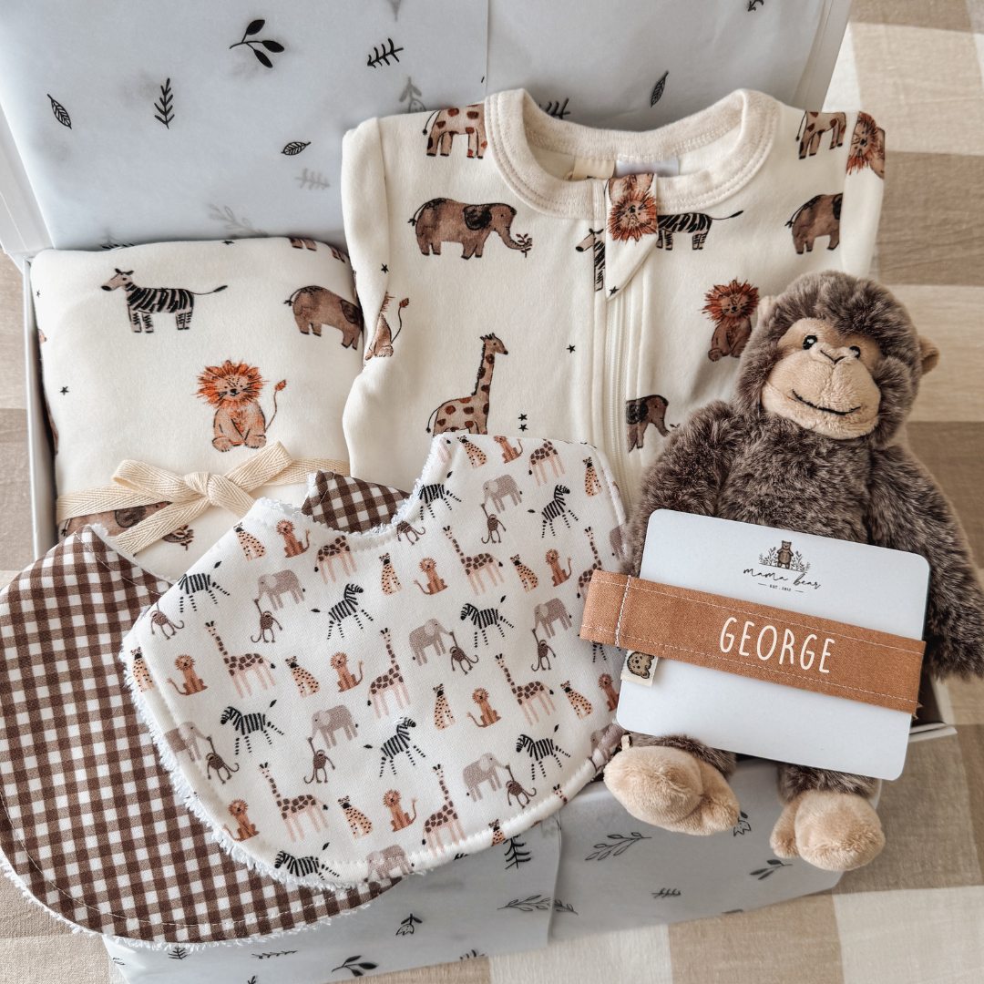 Personalised safari baby gift box featuring animal print zipsuit, handmade bibs, matching dummy clip and soft plush monkey rattle.