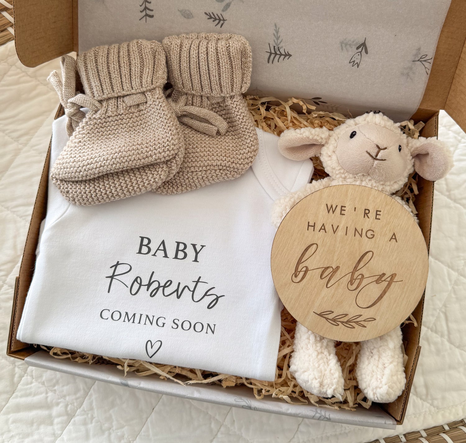 Baby announcement gift set with booties, blanket, and plush lamb toy in a box.