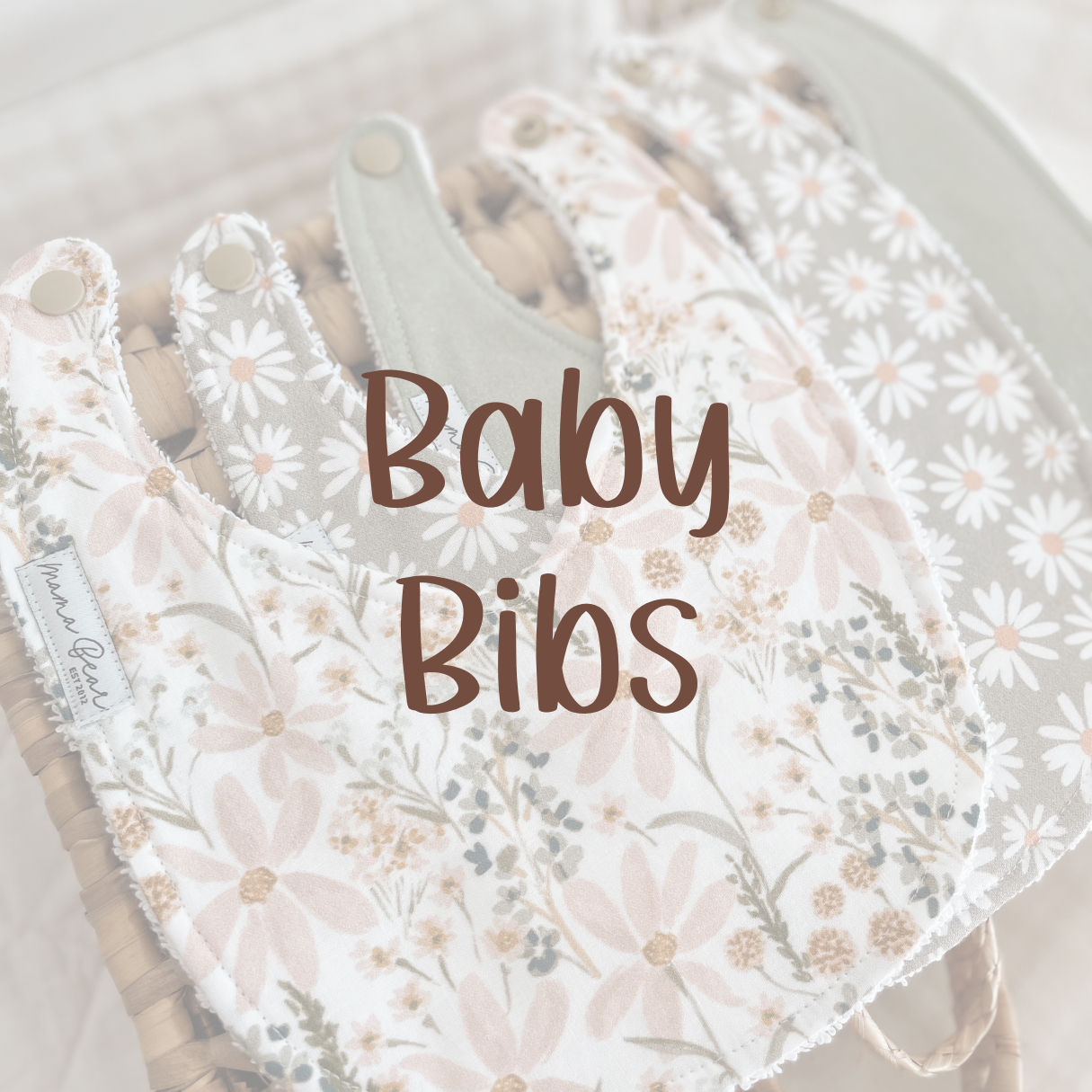 Three handmade bibs, floral pastel pink, sage daisy print & solid sage print. The image is blurred with brown text on top saying 'Baby Bibs'. Clickable link which takes you to entire baby bib collection.