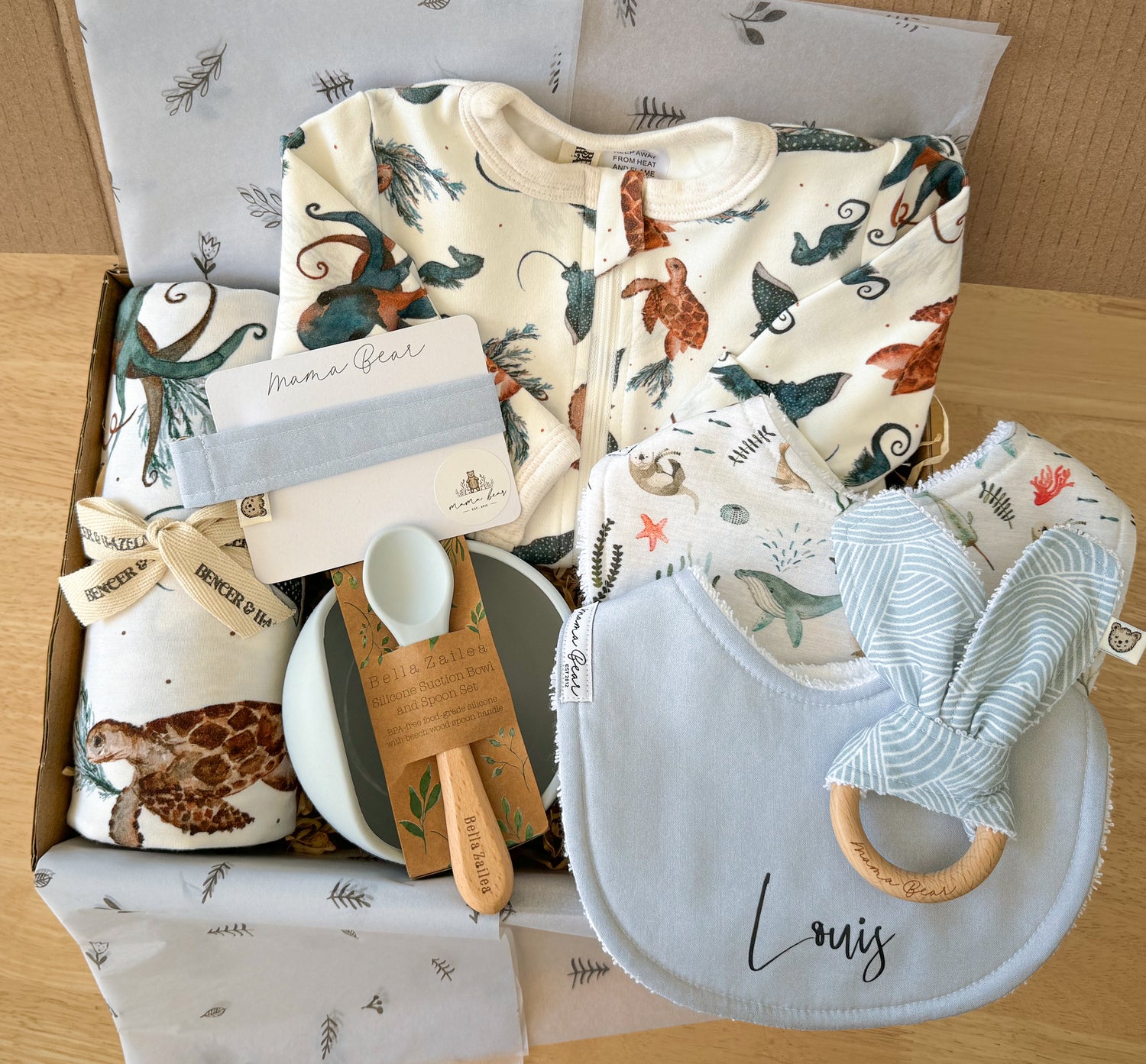 Baby shower gift box or newborn baby gift for boy, blue ocean theme. Gift box has a zipsuit and matching swaddle with sea turtles, sting rays & seahorse on it, coordinating pale blue bib, dummy clip & teething ring & silicon bowl.