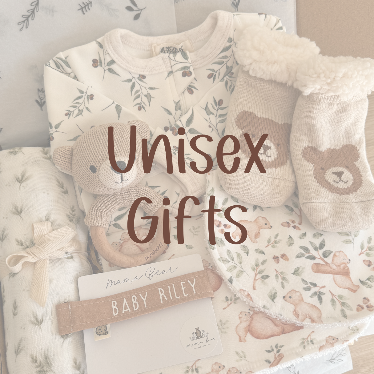 A unisex neutral baby gift box which includes a zipsuit with olive leaves on it. A swaddle with very light small leaves all over it and a white background. There is a pair of light brown socks with bear faces on it. A matching rattle with a crochet little brown bear. A personalised tan dummy clip with white text that says 'baby riley'. A burp cloth which has green leaves and a mummy & baby bear cubs  playing on it and a matching bib. The image has a white cast over it and says 'Unisex Gifts'.