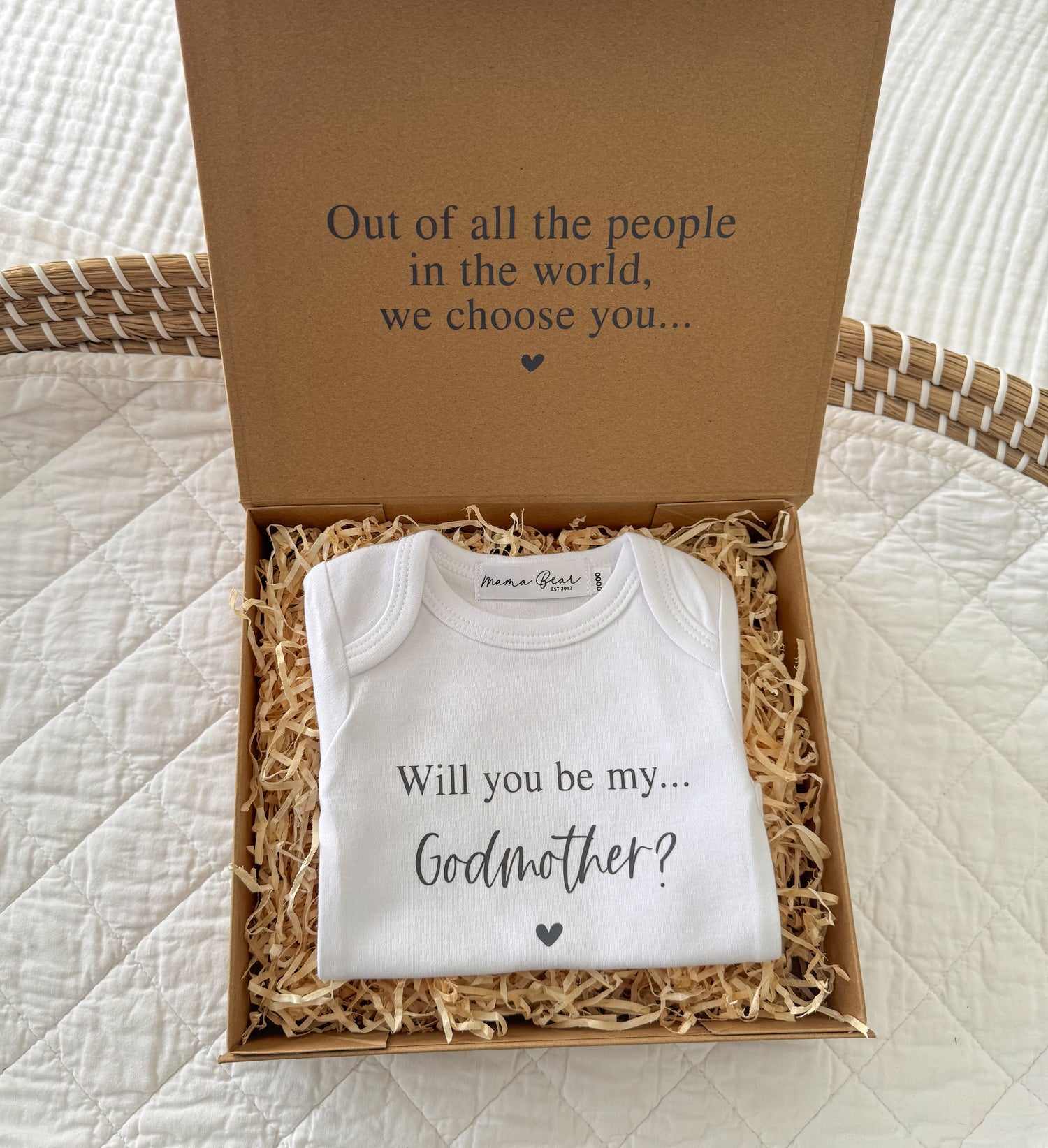 Unique gift to ask special person to be a Godparent to baby. Brown kraft box with message on inside of lid "Out of all the people in the world, we choose you..." Inside box is a baby onesie that says "Will you be my Godmother?"