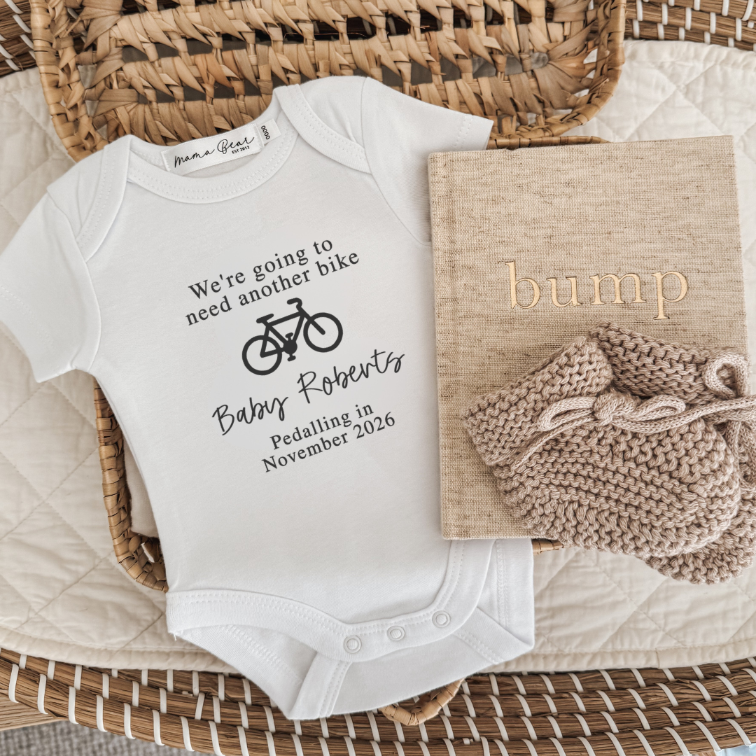White onesie with black text ' We're going to need another bike *picture of bike* Baby Roberts Pedalling in *due date*
