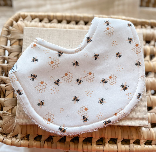 White handmade baby bib with tiny black and golden bee and honeycomb illustrations, backed with absorbent terry towelling – ideal for dribble and teething babies, made in Australia.