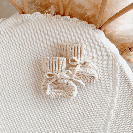 Knitted baby booties in a cream colour.