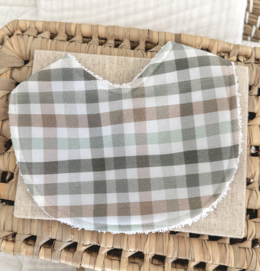 Handmade baby bib with a checkered plaid pattern in moss green, taupe brown, and pale grey on soft cotton, contoured for newborn comfort