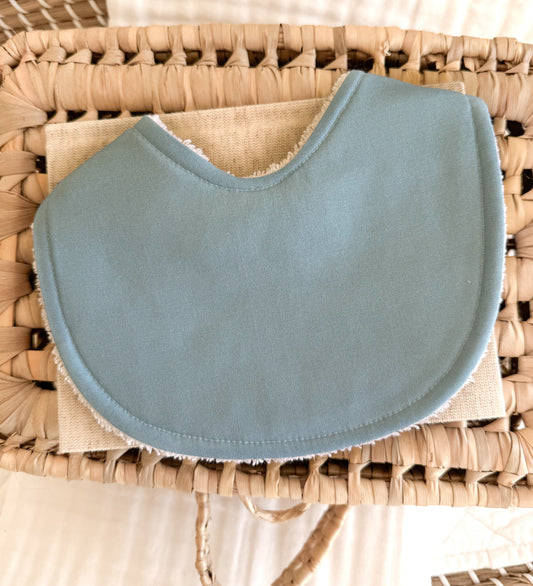 Flat lay of baby boy bib in a plain sky blue shade.