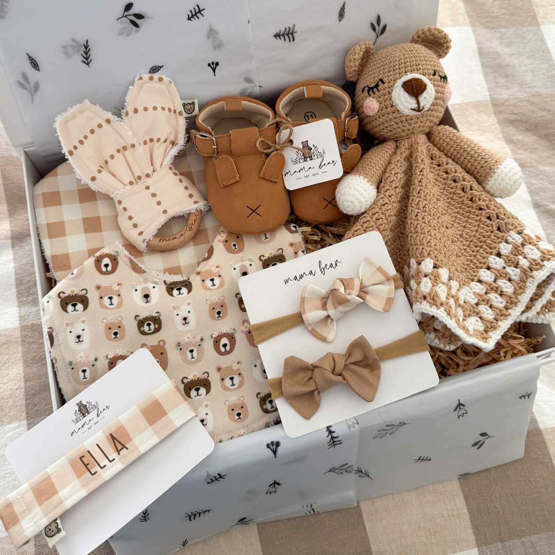 Gift for new baby girl. Crochet brown teddy bear comforter in soft brown and white colours. Tan bunny baby shoes. A personalised dummy clip in a mushroom beige tone gingham. Matching bib. Another bib with a beige background and little bear faces wearing flower crowns. two matching hair bows and a beige spot teething ring.