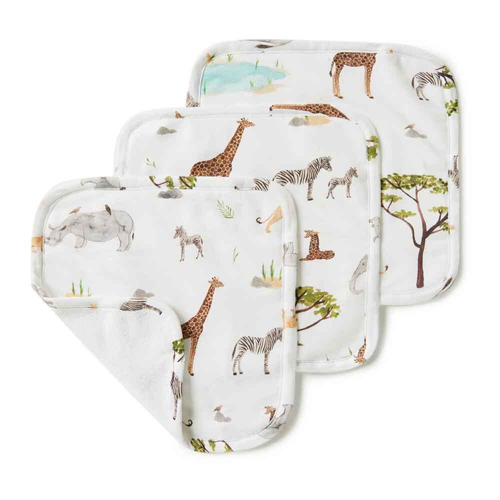Three square baby washcloths with rounded corners, stacked diagonally. The white fabric features a safari animal print with giraffes, zebras, a rhinoceros, and trees.