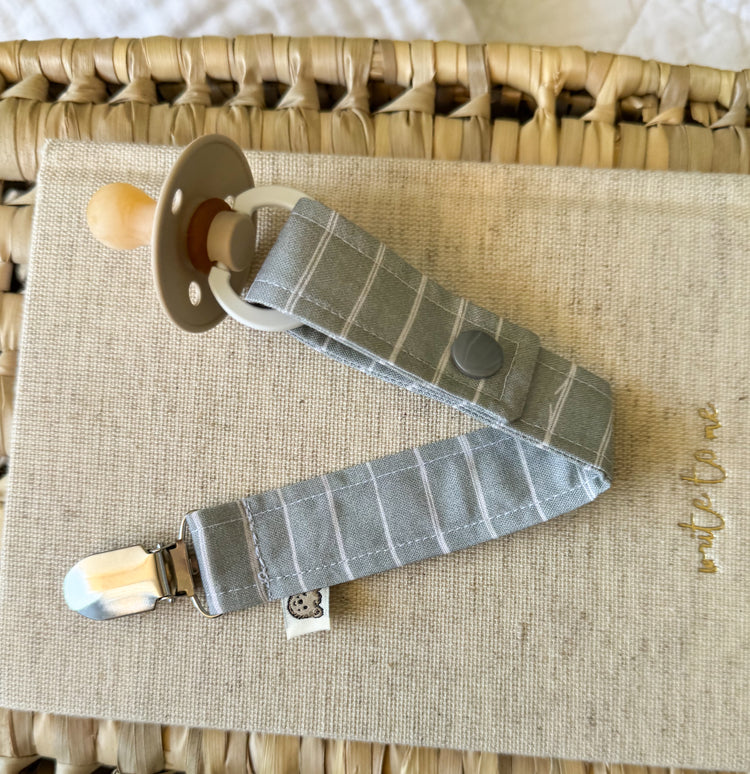 A fabric sage green stripe dummy clip with metal clasp and snap for dummy