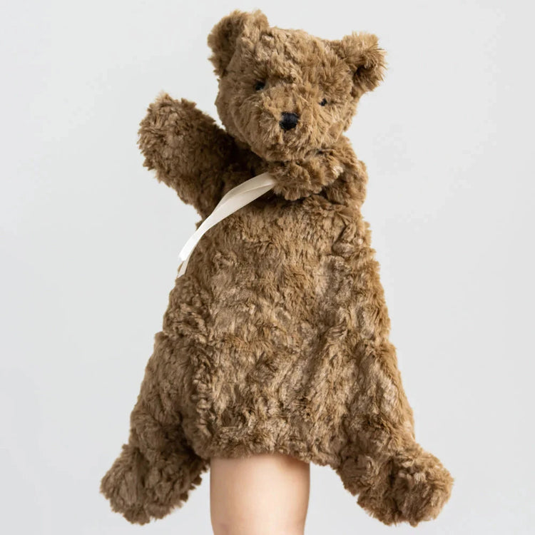 Brown teddy bear held by a person against a light gray background