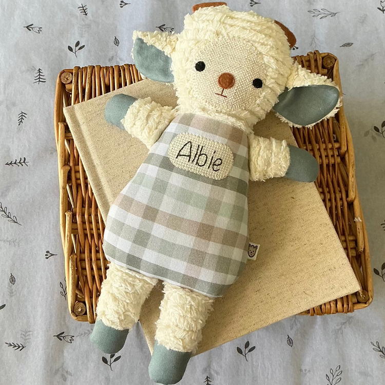 A handmade soft lamb keepsake. Lamb has white arms, legs and face. With blue paws and a blue, sage and brown gingham print  body. Hand stitched baby name in middle of lambs body. This would make a very unique newborn gift.