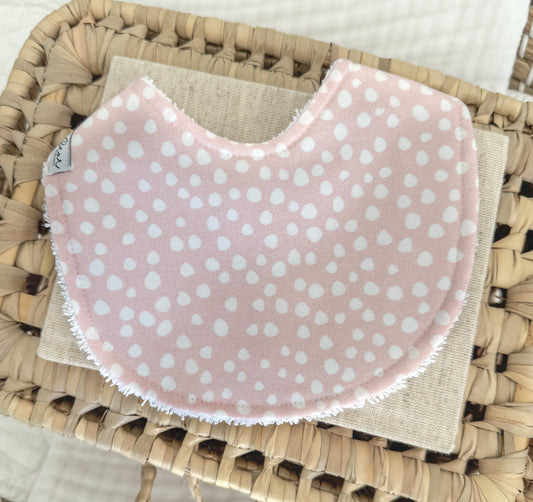 Handmade baby girl bib with a white sprinkle dot pattern on blush pink cotton, contoured for newborn comfort and ideal for gifting or daily use.