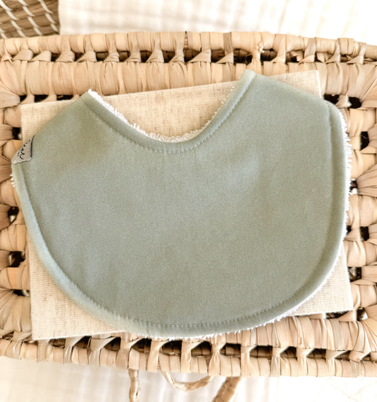 A handmade baby bib in a soft sage green solid tone. 