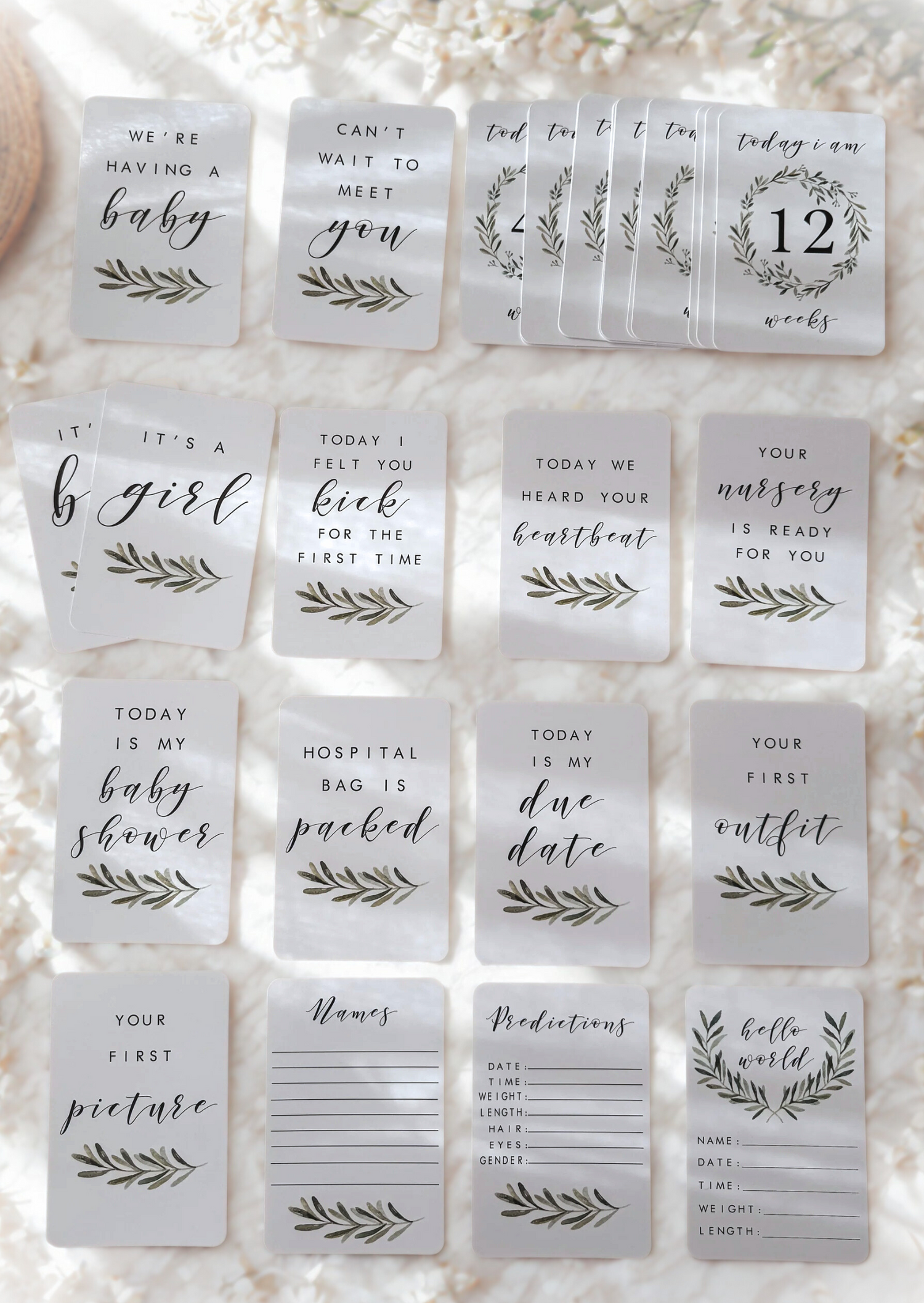 Set of cards with baby shower and pregnancy milestone messages on a textured surface.