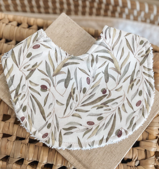 Handmade baby bib with a delicate olive branch pattern in earthy greens and plum tones on a neutral background; backed with absorbent terry towelling, ideal for newborns and teething babies.