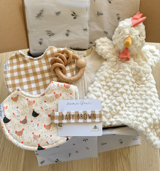 Unique baby shower gift idea, newborn gift idea. Beige, neutral tones. Gift box has 2 x handmade bibs (one with chickens the other caramel check), a matching dummy clip personalised with babies name. A beige growsuit, wooden rattle and flat chicken comforter toy.