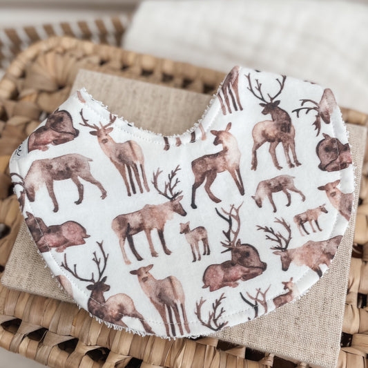 White baby bib with a woodland animal print featuring various deer, fawns, and antlers in brown watercolour tones. Backed with terry towelling, perfect for dribbles and teething.
