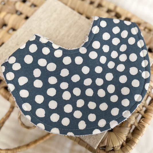 Cobalt blue baby bib with cream polka dots and terry towelling backing. Designed to be absorbent for drool, spills, and teething.