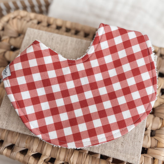 Baby bib featuring a red and white gingham check pattern, backed with absorbent terry towelling. Ideal for Christmas or everyday use.
