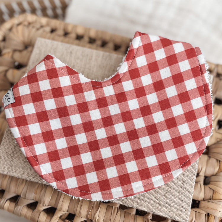 Baby bib featuring a red and white gingham check pattern, backed with absorbent terry towelling. Ideal for Christmas or everyday use.