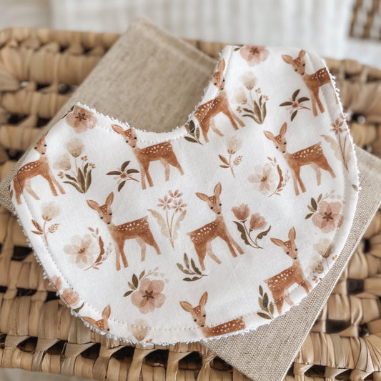 Baby bib with woodland deer / fawn and floral pattern in soft brown, blush, and cream tones. Made with absorbent terry towelling, ideal for newborn dribbles and teething.