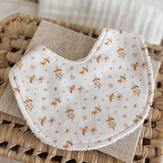 Pale pink baby bib with a dainty pattern of golden bees and tiny blush flowers. Backed with absorbent terry towelling, perfect for newborn dribbles, teething, and everyday mess.